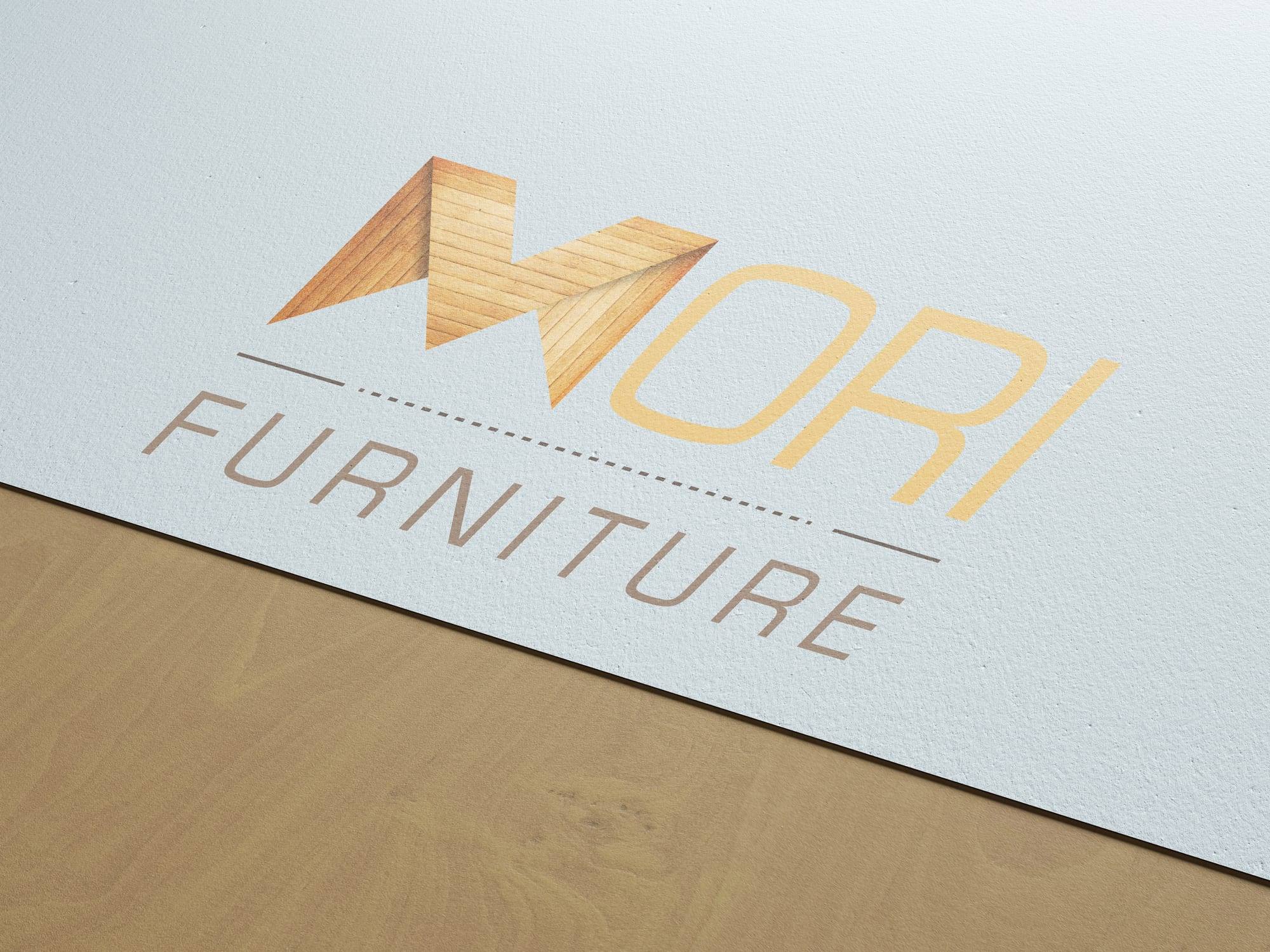Mori Furniture logo, with a wood-grain letter M, printed on a sheet of paper resting on wood